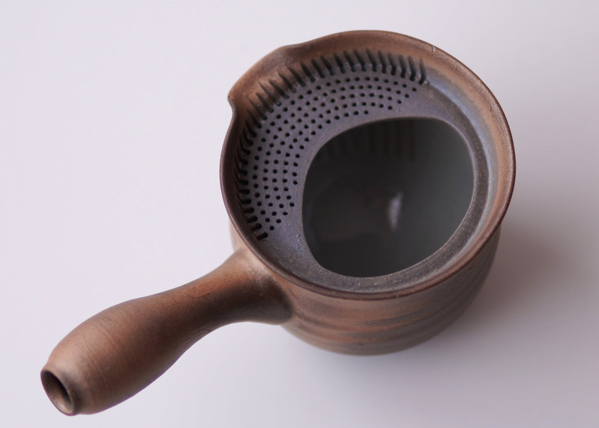 Ceramic tea infuser with handle on a white background