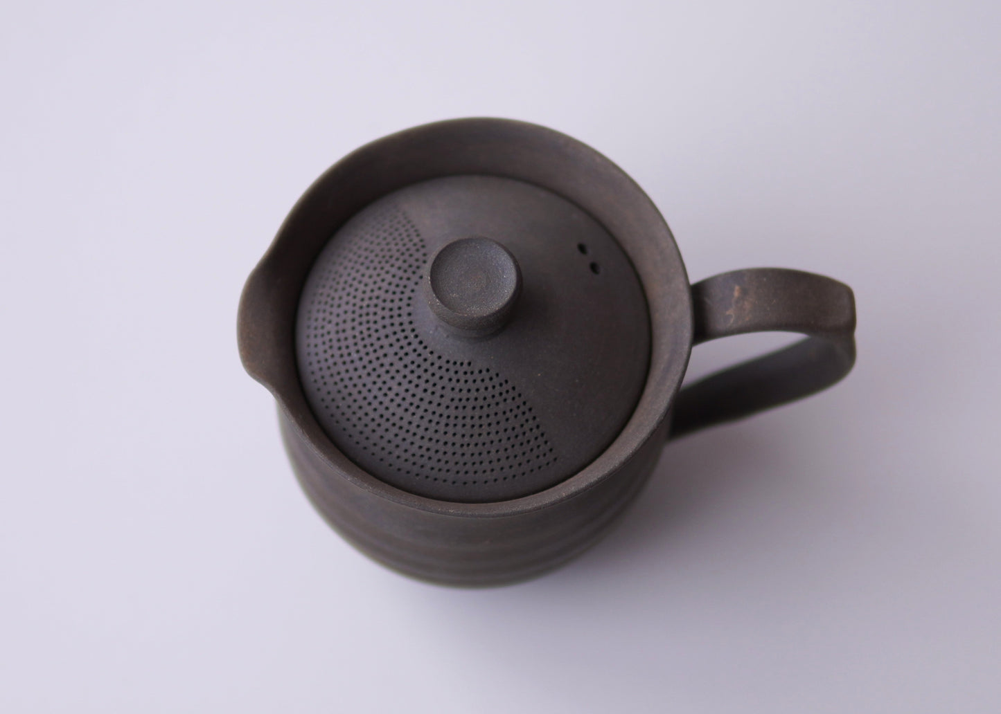 Black ceramic teapot with lid on a white background
