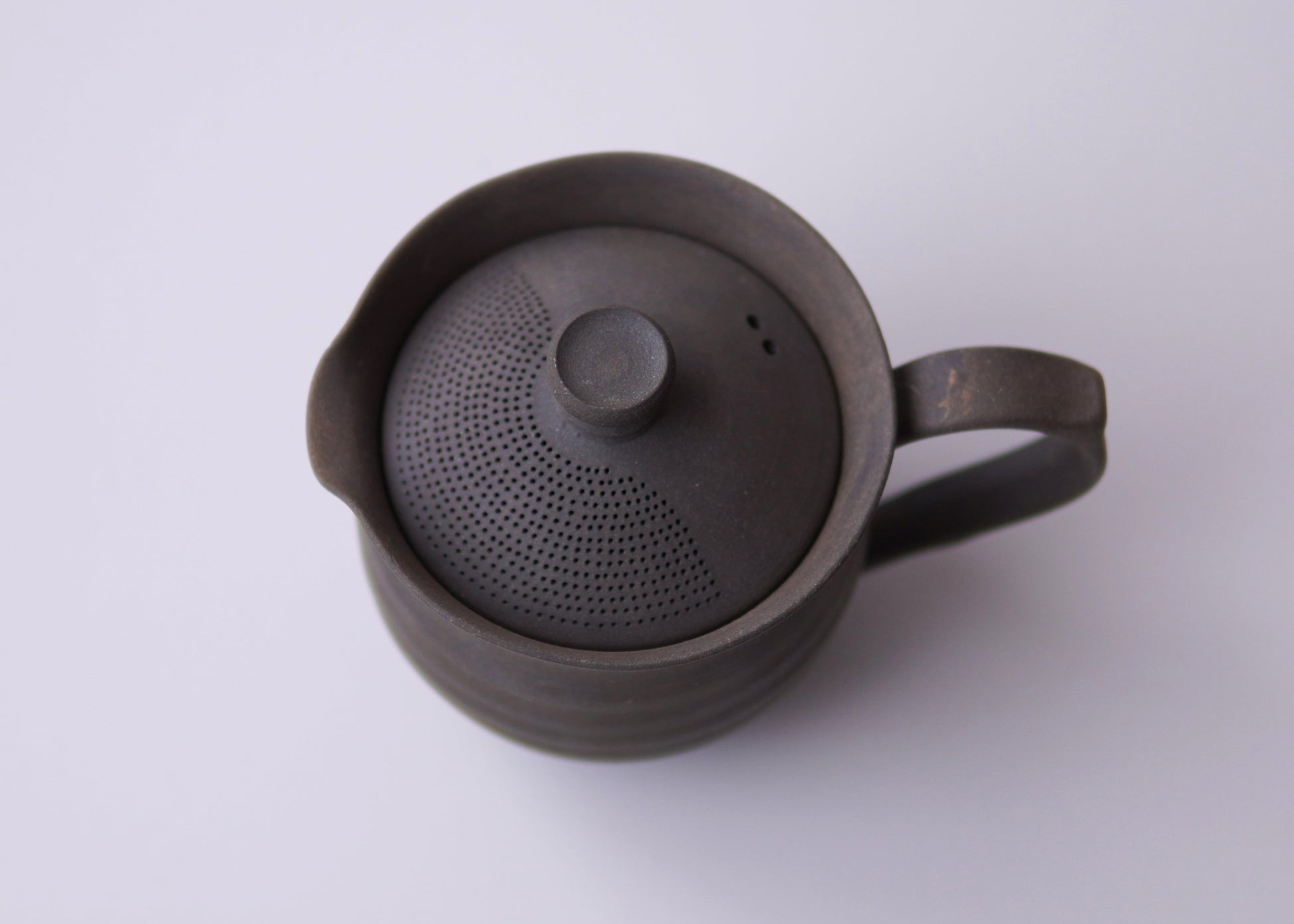 Black ceramic teapot with lid on a white background