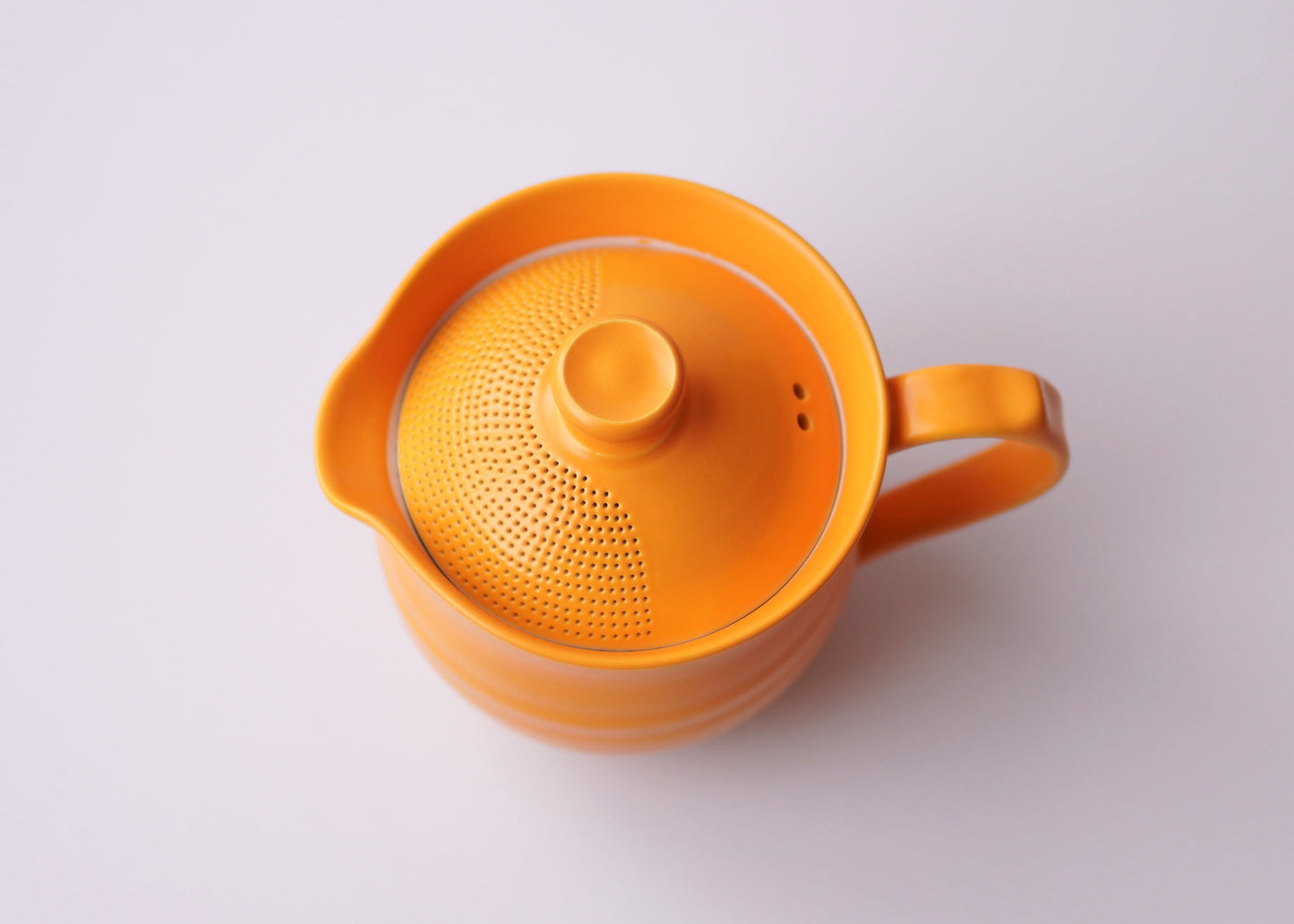 Orange ceramic teapot with lid on a white background
