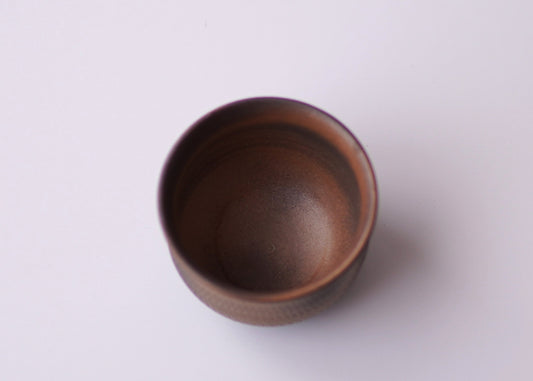 Brown ceramic cup on a light white background