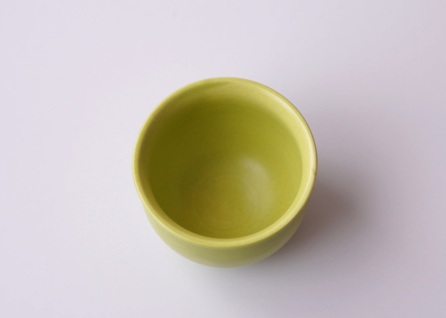 Green ceramic teacup on a white background