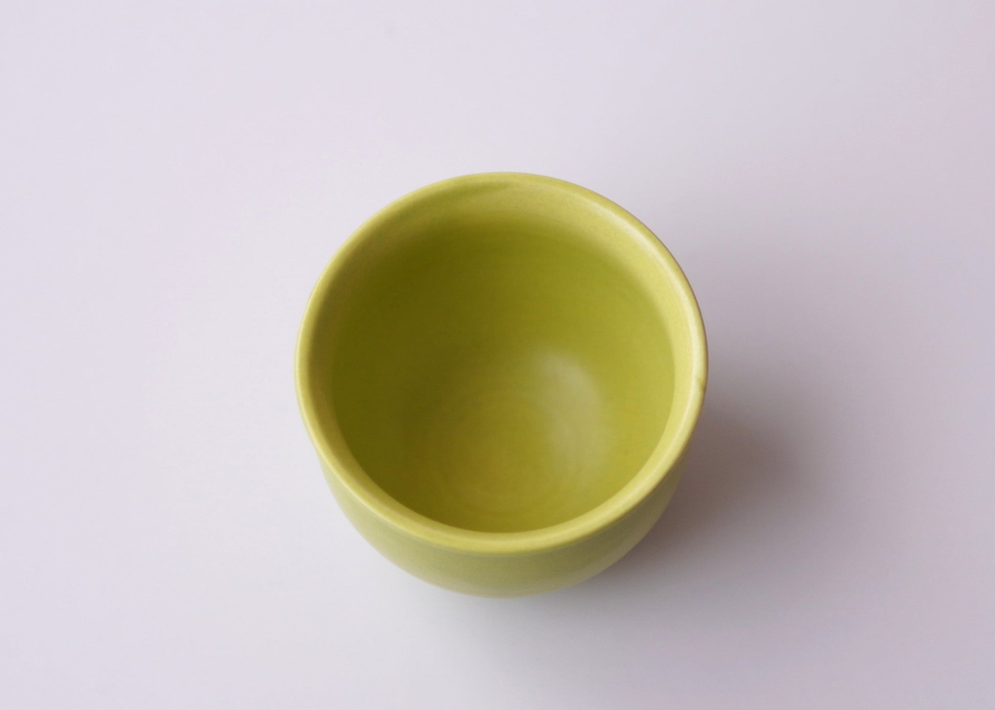 Green ceramic teacup on a white background