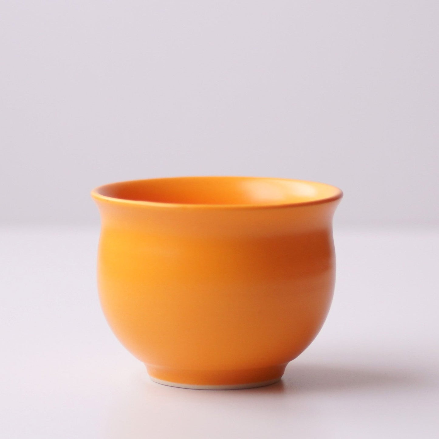 Orange ceramic cup on a light gray background