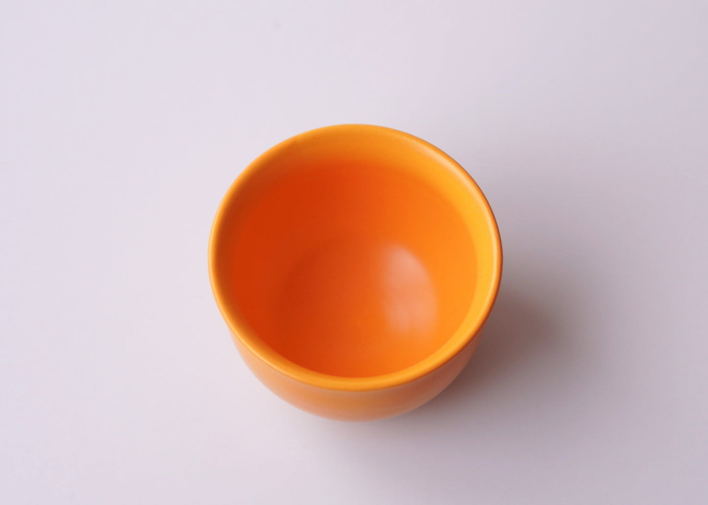 Orange ceramic teacup on a white background