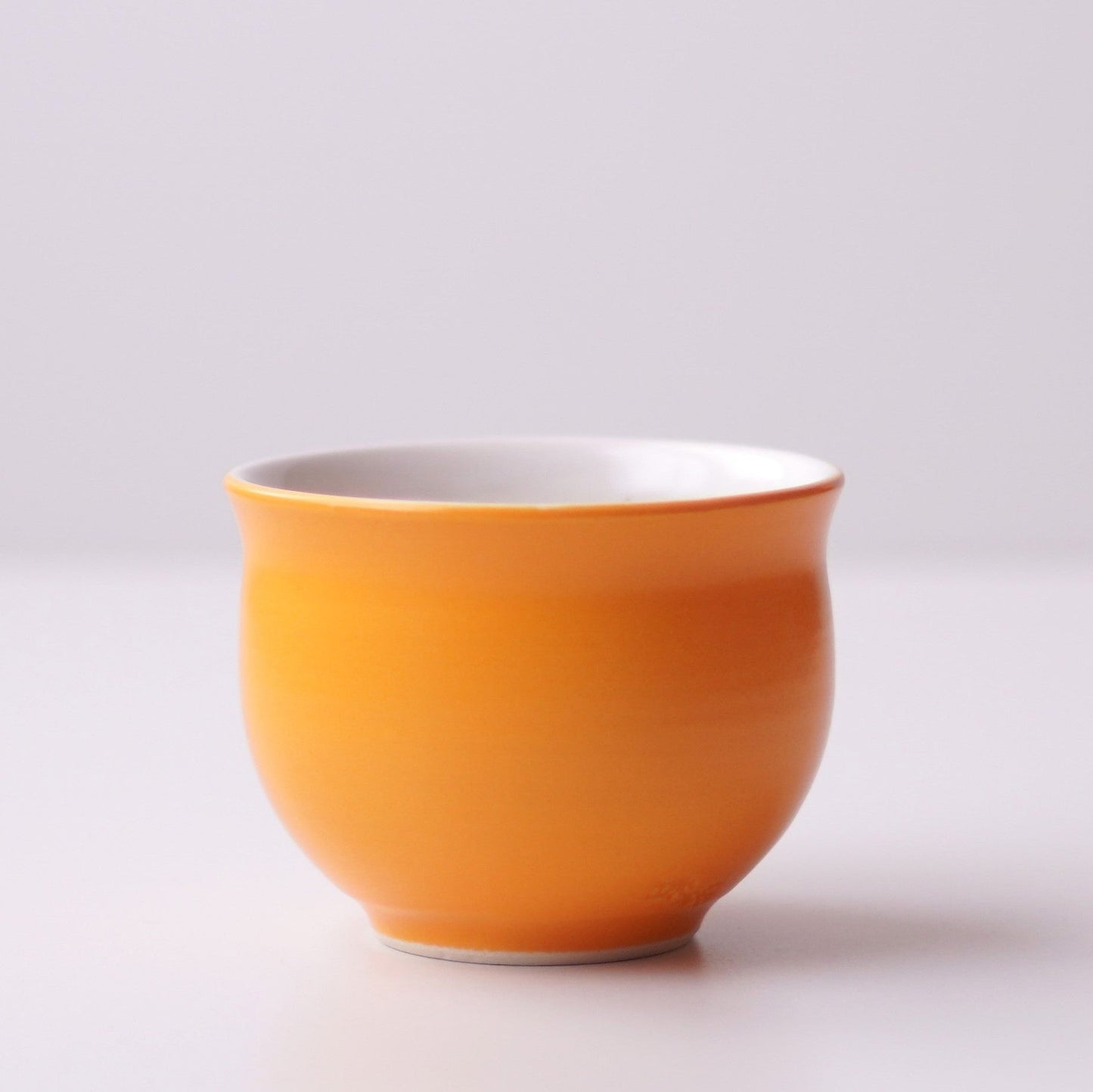 Orange ceramic teacup on a white background